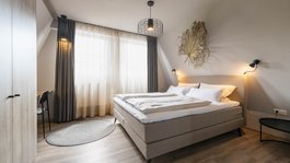 Seeblick: Urlaub am See in NRW Modernes Schlafzimmer mit Doppelbett, Gardinen und minimaler Dekoration