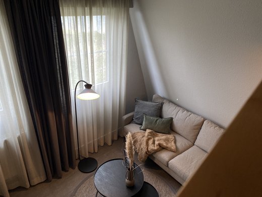 Unsere Appartements am See Gemütliches Wohnzimmer mit Sofa, Stehlampe und Kaffeetisch mit Dekoration