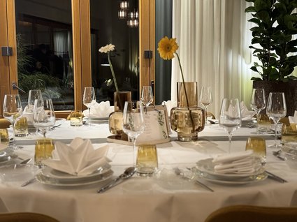 Urlaub im Apartment mit Seeblick Festlich gedeckter Esstisch mit weißen Servietten und Blumenvasen