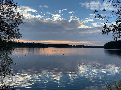 Hotel Seeblick in Gronau See mit spiegelndem Himmel und zwei Segelbooten am Horizont bei Sonnenuntergang