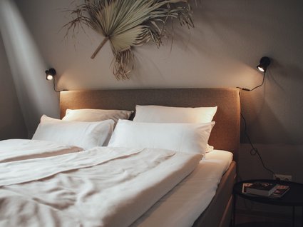 Aparthotel am See in Gronau Gemütliches Doppelbett mit weißen Kissen und Decken in modernem Schlafzimmer