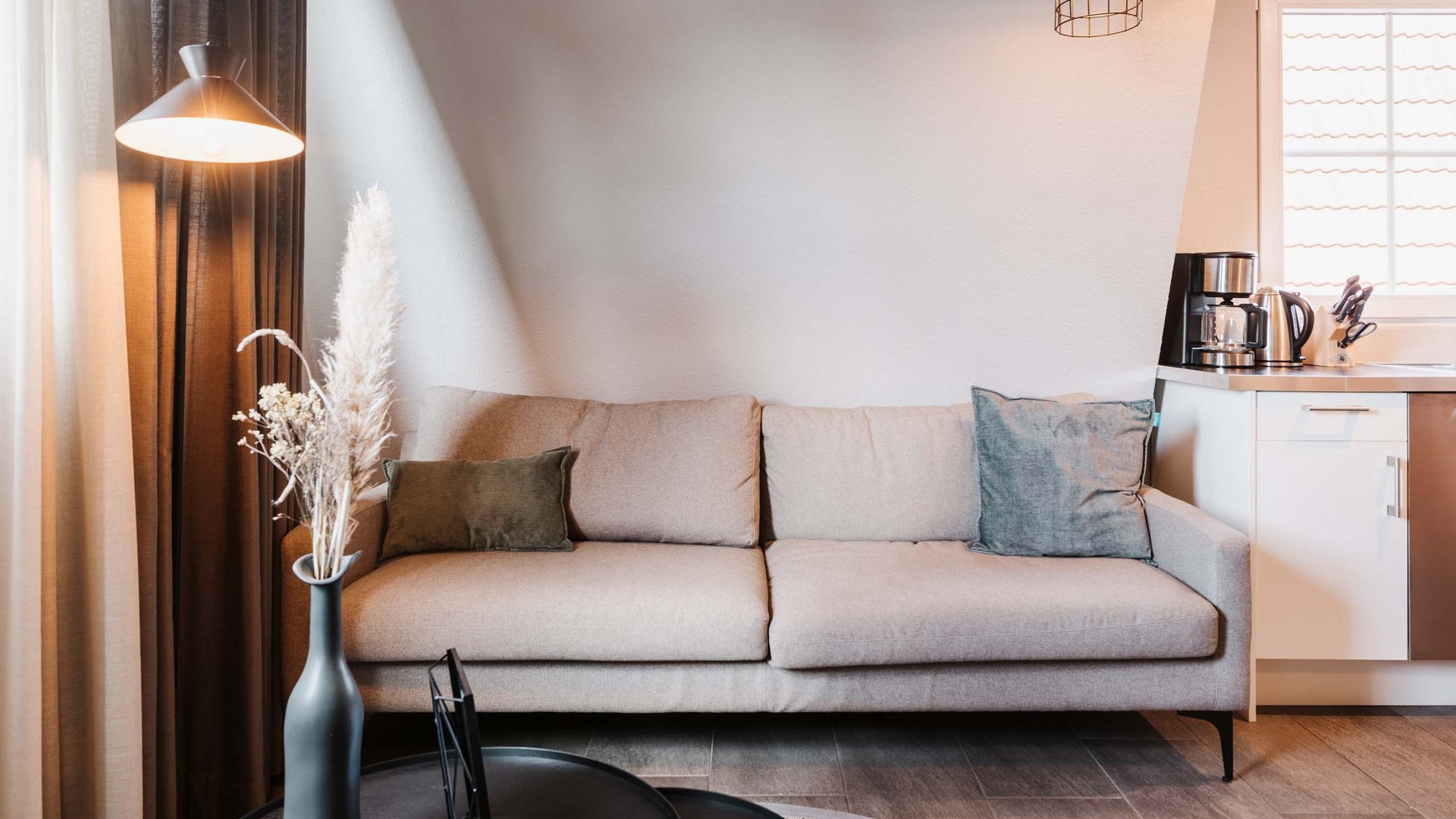 Unsere AGBs Beiges Sofa vor weißer Wand mit Stehlampe und Vase