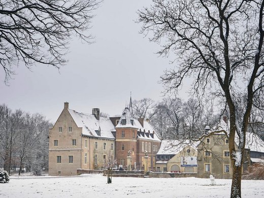 Urlaub am See in NRW - sogar im Winter wunderschön! Schloss mit Schnee bedeckt und kahlen Bäumen im Winter