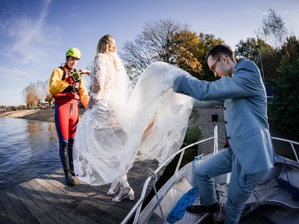 News vom Hotel direkt am See in NRW Braut mit Kleid und Bräutigam steigen von Boot auf Steg mit Rettungsschwimmer