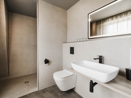 Urlaub im Apartment mit Seeblick Modernes Badezimmer mit hängendem WC, Waschtisch und beleuchtetem Spiegel