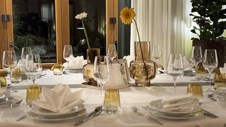 Appartementhotel Seeblick: Bildergalerie Eleganter gedeckter Esstisch mit gelben Blumen in Vasen im Innenraum