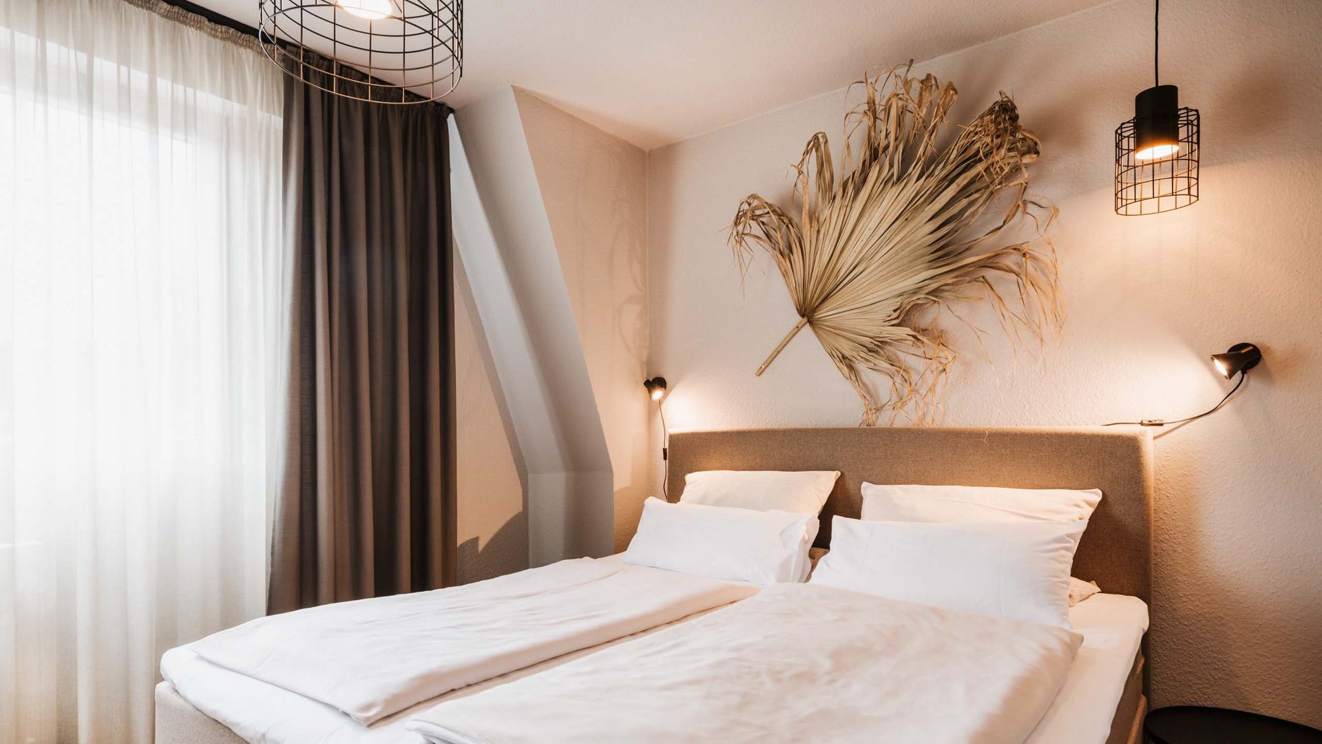 Unsere Appartements am See Modernes Schlafzimmer mit Doppelbett und dekorativem getrocknetem Blatt an der Wand