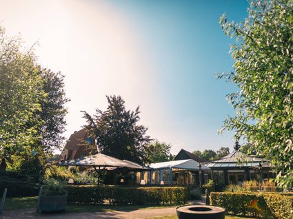 Urlaub im Apartment mit Seeblick Sonniger Garten mit Pavillons, Büschen und Bäumen an einem klaren Tag