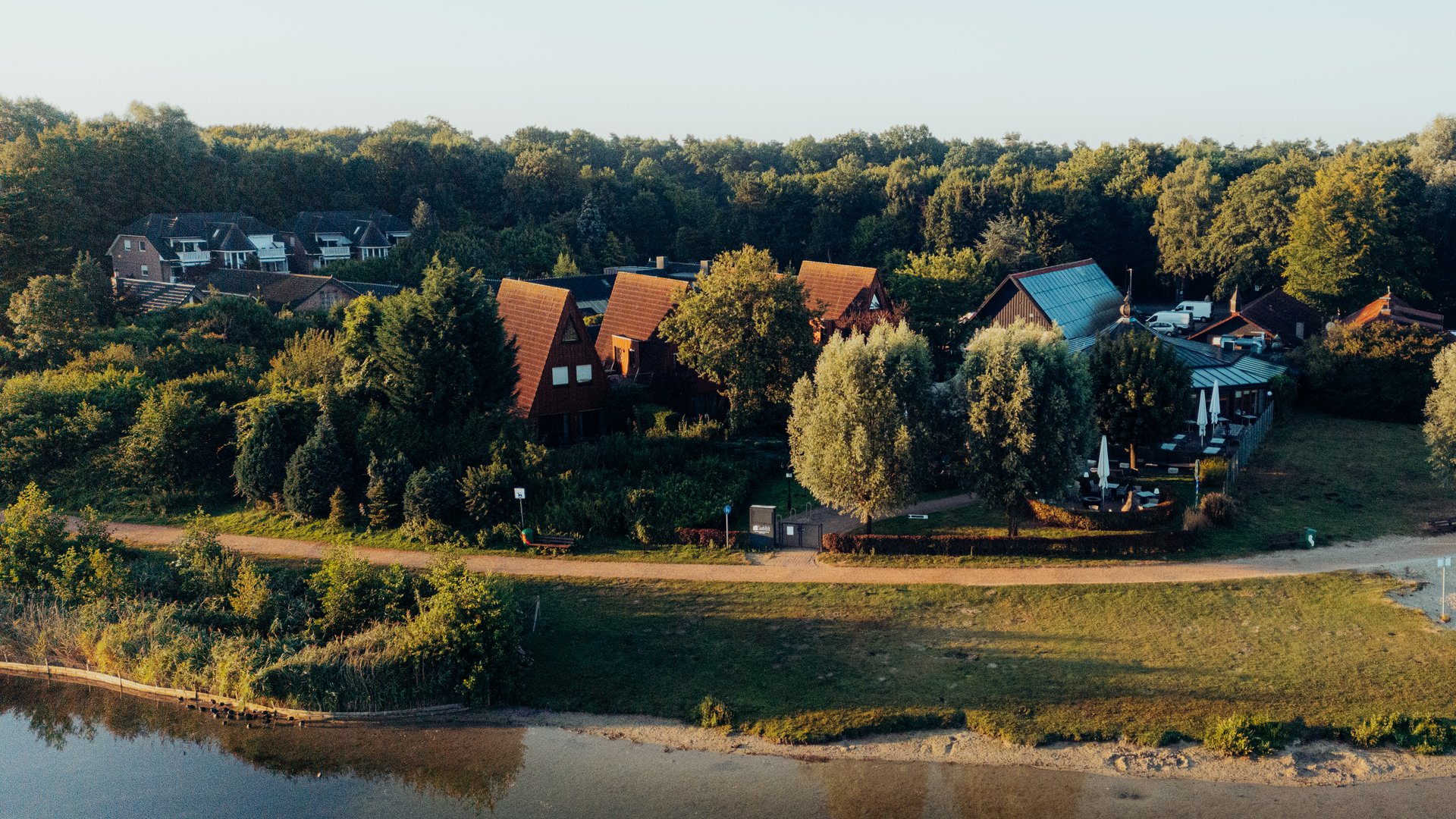 Jobs im Hotel Restaurant Seeblick in Gronau Dorf mit roten Häusern am Ufer und Wald im Hintergrund bei Sonnenuntergang