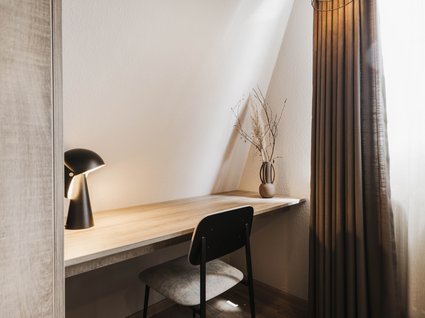 Urlaub im Apartment mit Seeblick Minimalistischer Arbeitsplatz mit Holzschreibtisch, Stuhl, Lampe und Vase