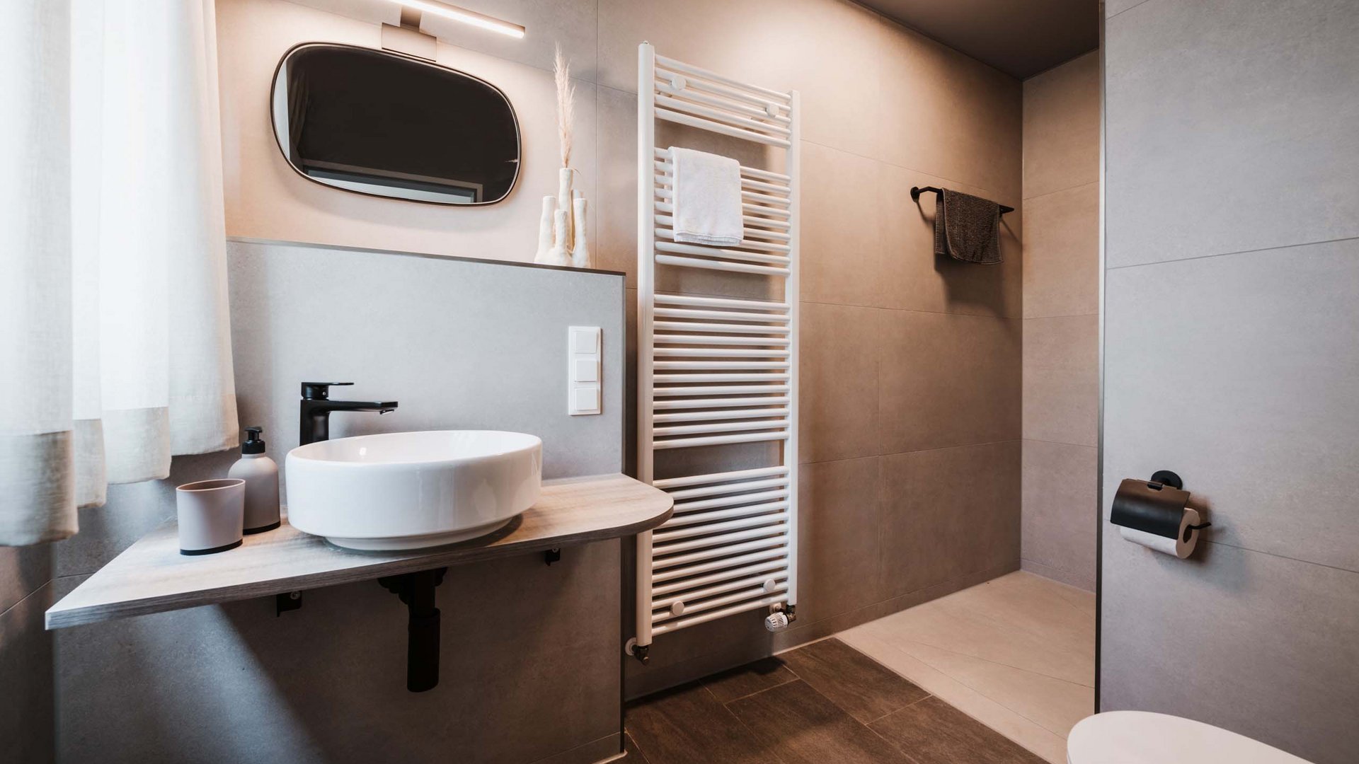 Unsere Appartements am See Modernes Badezimmer mit rundem Waschbecken und Handtuchheizung