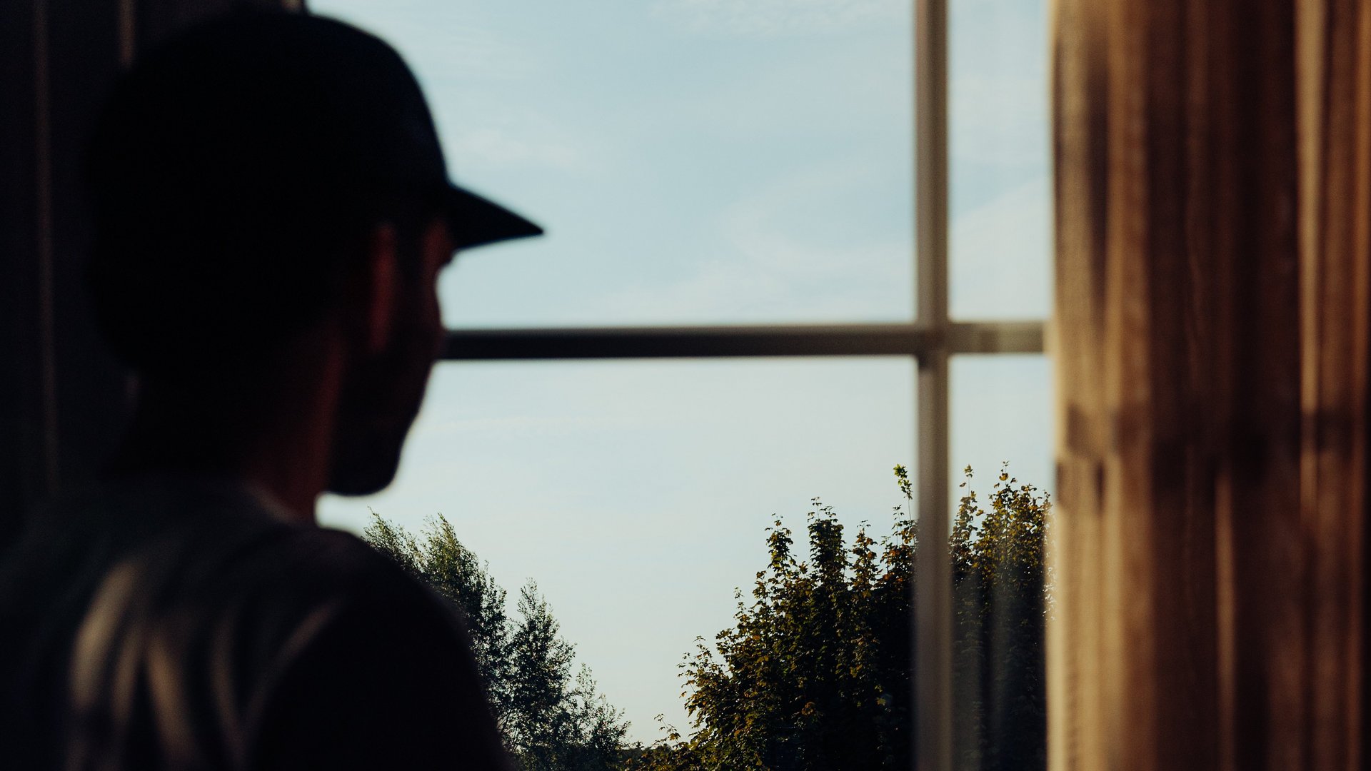 Jobs im Hotel Restaurant Seeblick in Gronau Schattenhafte Figur blickt aus Fenster auf Bäume und Himmel