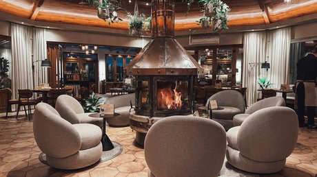 Appartementhotel Seeblick: Bildergalerie Gemütlicher Sitzbereich mit rundem Kamin und hängenden Pflanzen in einem Restaurant