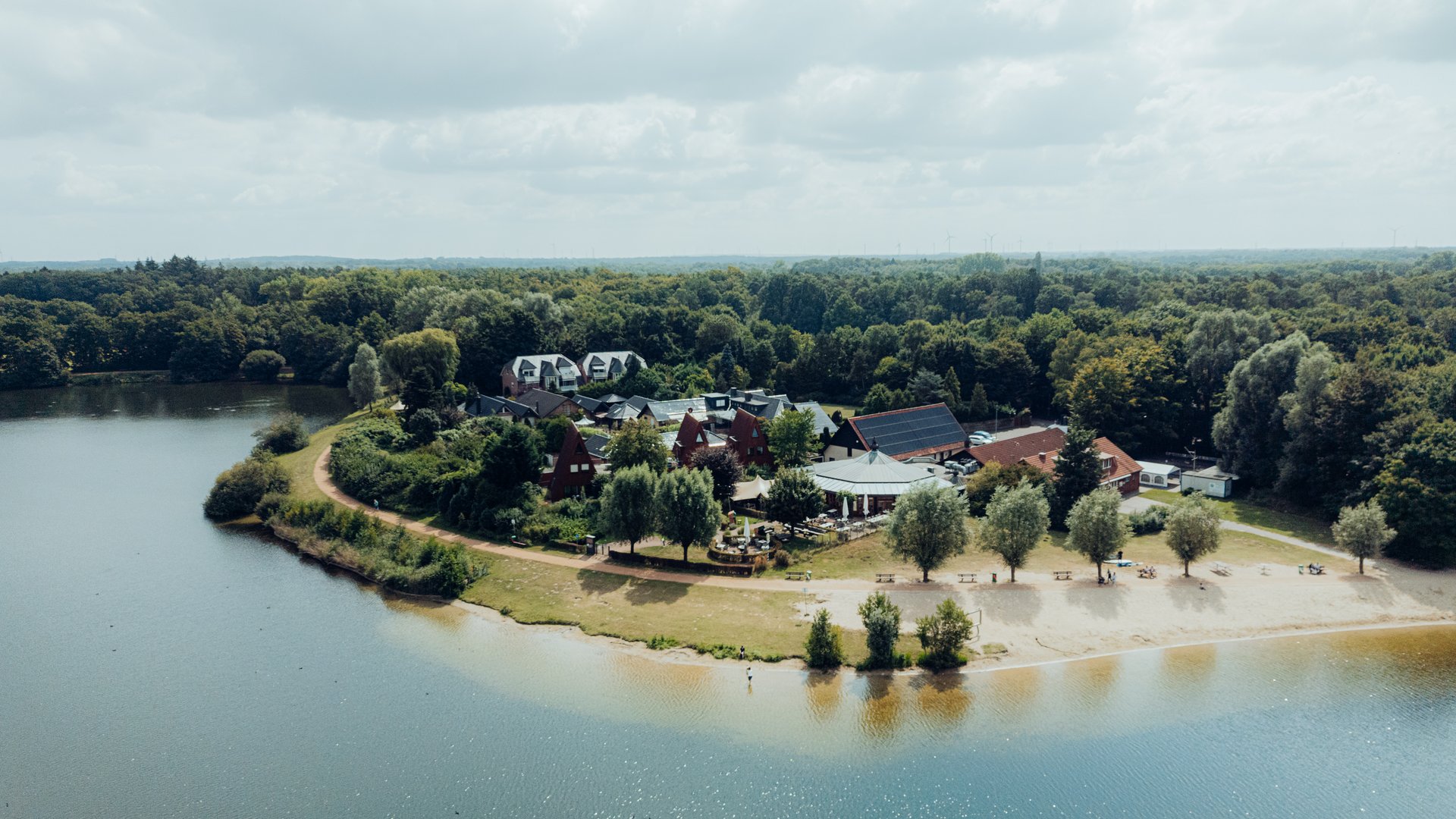 Jobs im Hotel Restaurant Seeblick in Gronau Luftaufnahme einer Landspitze mit Häusern an einem See und umgeben von Wald