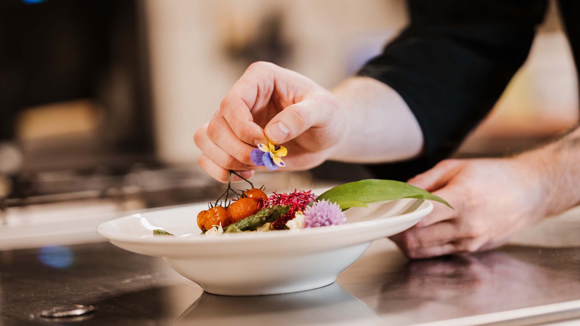 Seeblick Gronau: Urlaub inmitten der Natur Koch dekoriert Teller mit essbarer Blume und Gemüse
