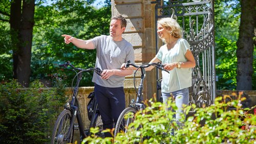 Restaurant Gronau: Seeblick Couple with bicycles, man pointing at something in a park