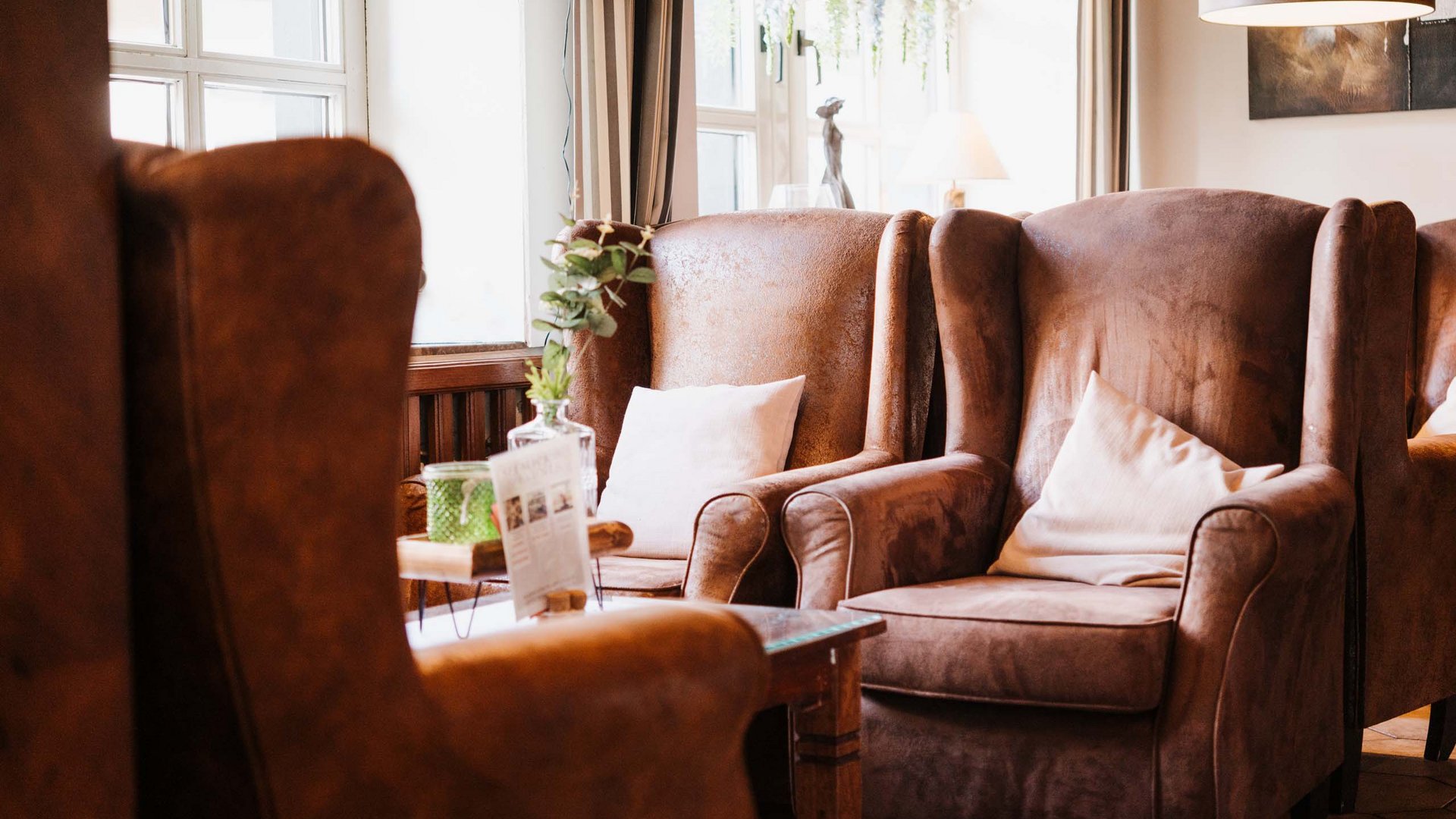 Seeblick Gronau: Urlaub inmitten der Natur Gemütliche braune Sessel mit weißen Kissen in einem hellen Raum