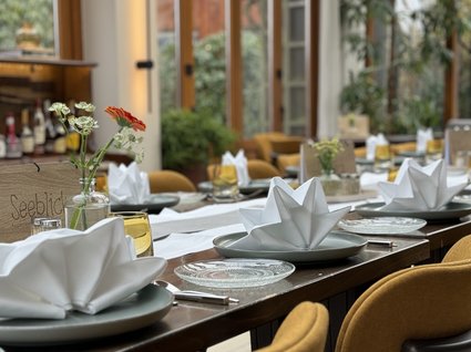 Restaurant Gronau: Seeblick Elegant set table in bright restaurant with yellow chairs and flower vases